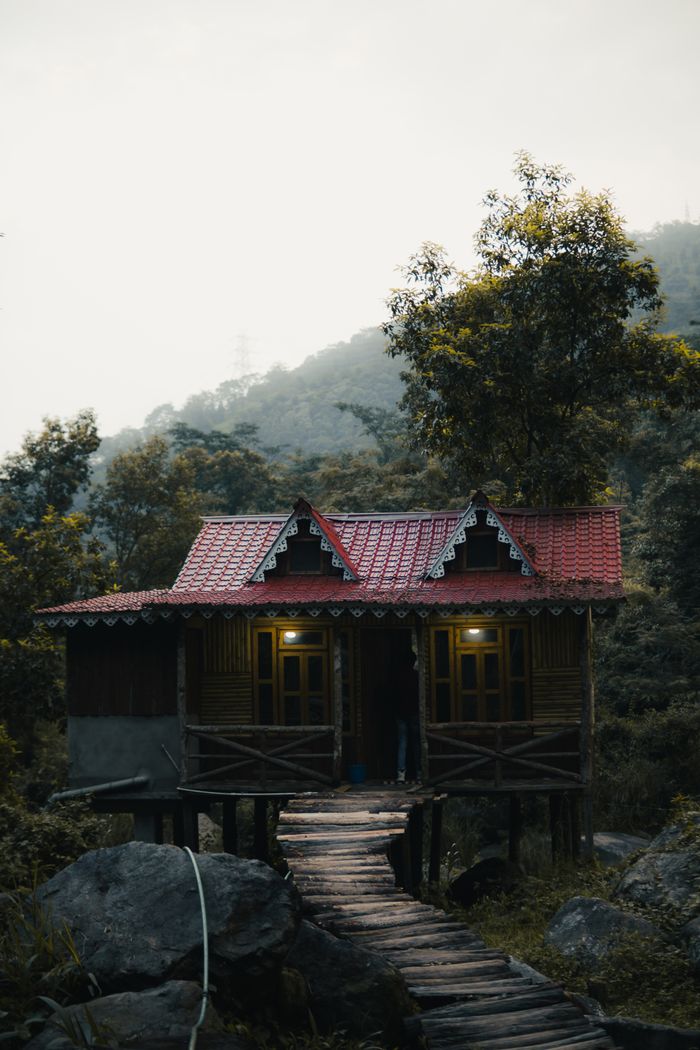 our-mission A picturesque rural house with red roof nestled in the lush hills of Darjeeling, India.