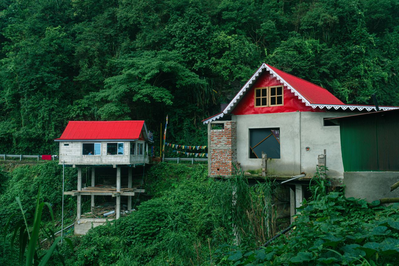 service-03 Charming houses with red roofs nestled in the lush hills of Darjeeling, India.